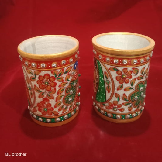 Two ornate ceramic cups with floral patterns on a red background